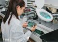 A woman assembling a circuit board.