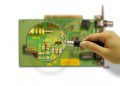 Person using a magnifying glass to look at a PCB
