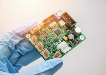 A gloved hand holding a PCB