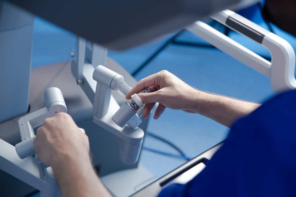 Surgeon using a robot to assist in surgery